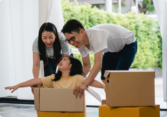 A happy family carrying boxes into their new home, smiling and excited for a fresh start, image